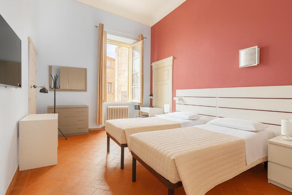 a bedroom with two beds and a red wall at Residenza del Capitano in Siena