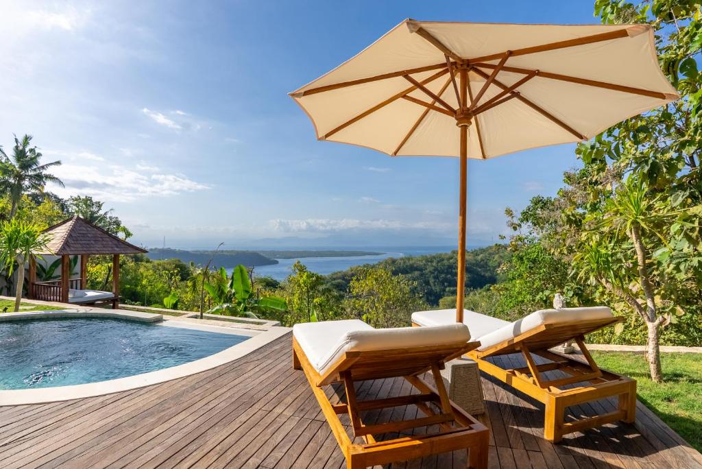 ペニダ島にあるMimpi Villas - Private Luxury & Romantic Villa with seaviewのスイミングプールの横にパラソルと椅子2脚