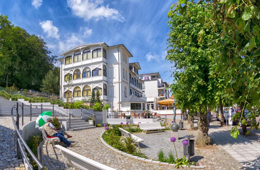 a woman sitting on a bench in front of a building at Haus am Meer Sellin App 5 und 6 by Meine Ferienzeit in Ostseebad Sellin