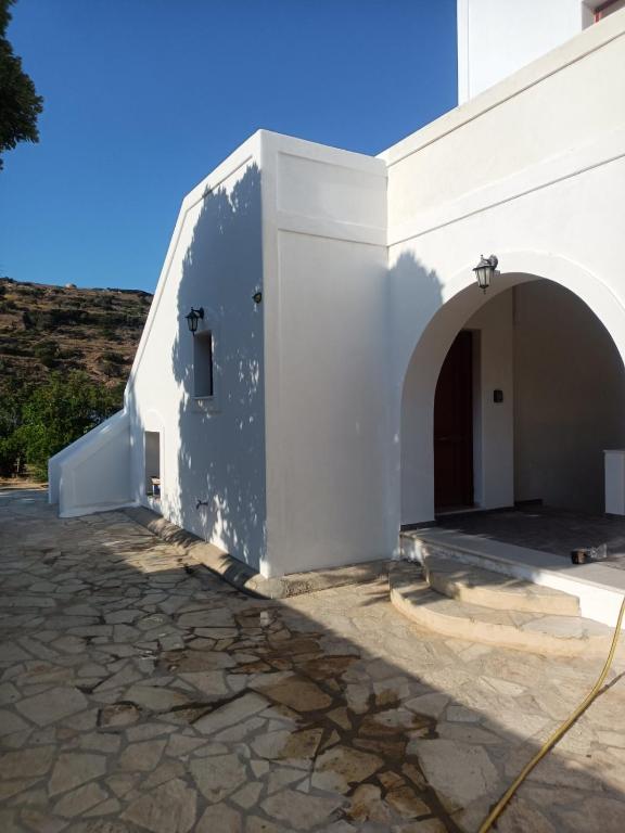 a white church with an archway next to a building at Lefkes Horizon in Lefkes