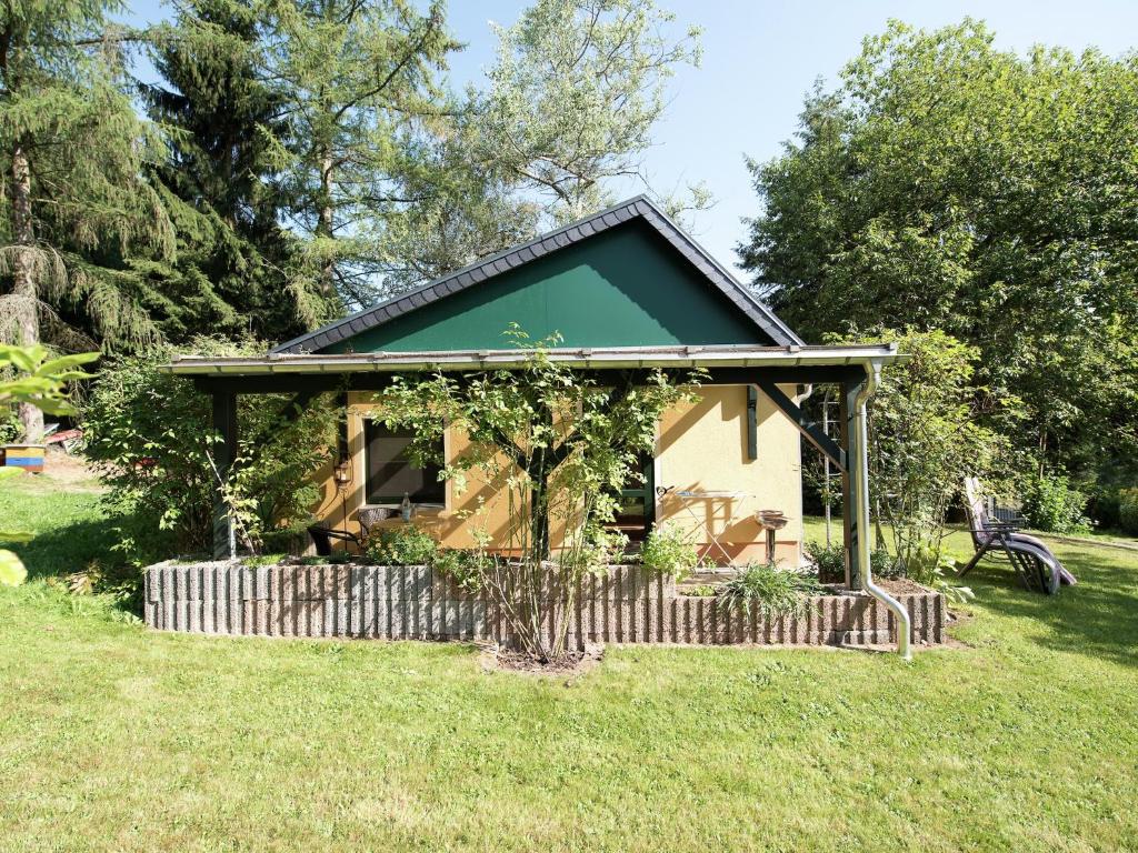 a small house with a green roof in a field at Cozy Escape in Walthersdorf in Scheibenberg