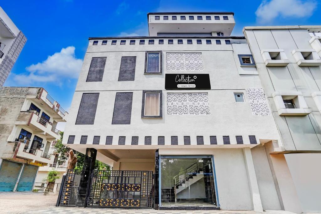 a tall white building with a black sign on it at Super Collection O Iskcon Temple Mansarovar Formerly Chinar Inn in Jaipur