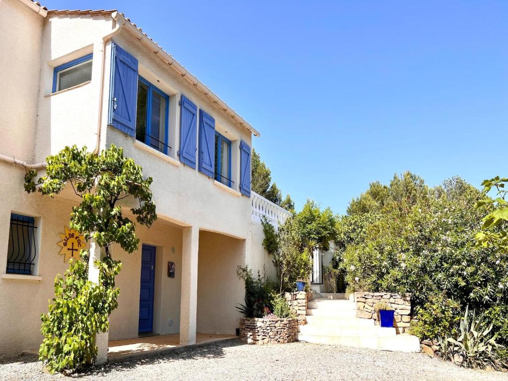 a white house with blue windows and a driveway at Modern villa with private pool in Pouzols-Minervois