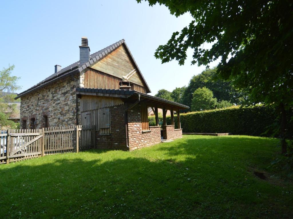 an old stone house with a fence and a yard at Chalet Retreat with Sauna in Robertville