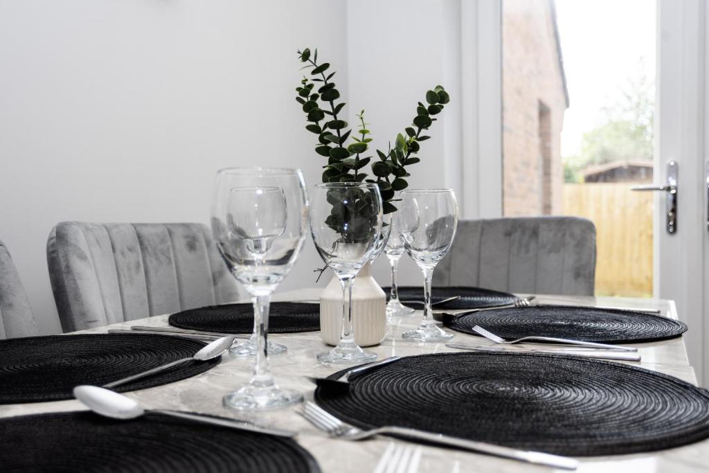 a table with plates and wine glasses on it at Central Telford Home - Sleeps 8 - Private Parking in Telford