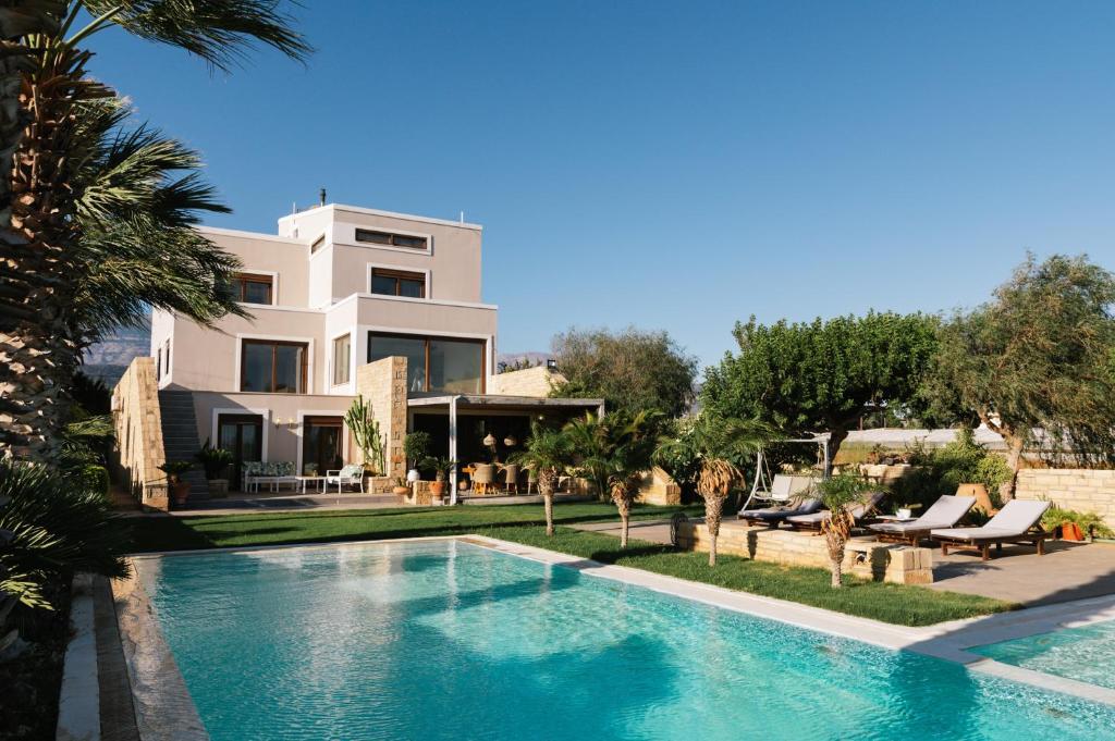 a villa with a swimming pool in front of a house at FOS signature living in Kókkinos Pírgos