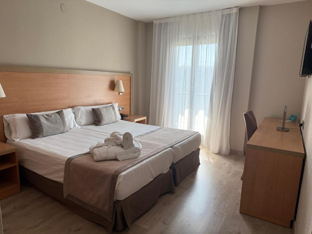 a bedroom with a bed with two stuffed animals on it at Hotel Real in Lleida