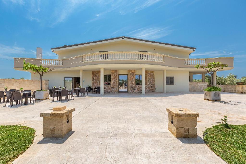 Casa grande con patio con mesas y sillas. en Agriturismo Cutura, en Parabita