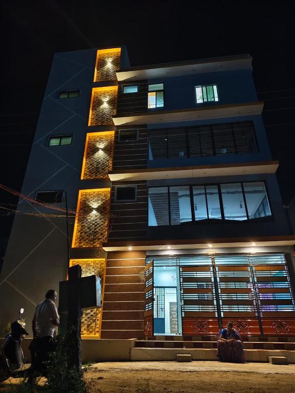 a building with people sitting in front of it at night at Rajeshwari Tower & Residency in Tiruvannāmalai