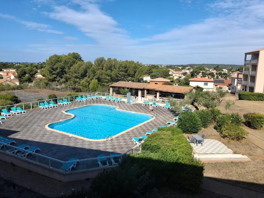 a large swimming pool with chairs and a building at Chez Laurette in Balaruc-les-Bains