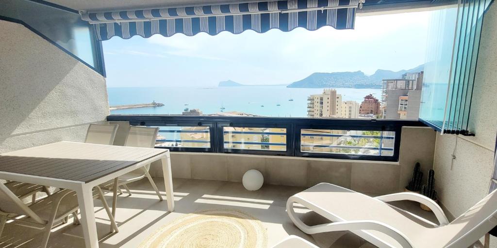 a balcony with a table and chairs and a large window at Blue Beach Apartment in Ifach