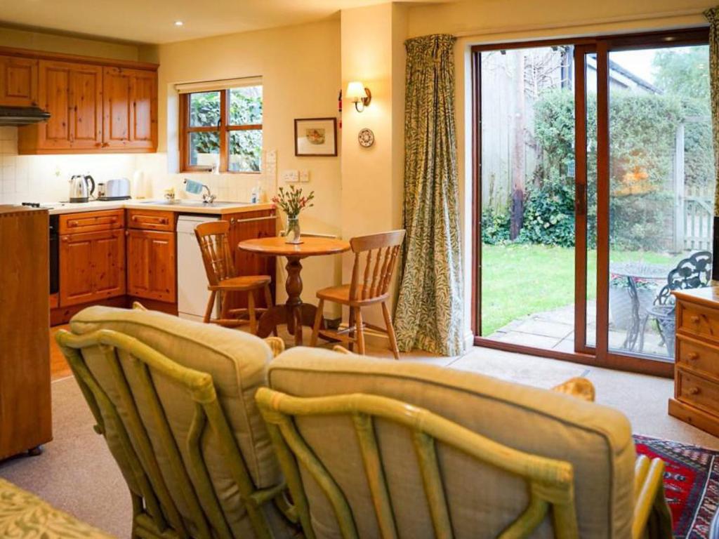 a kitchen with a table and chairs and a dining room at Honeysuckle Cottage in North Mundham