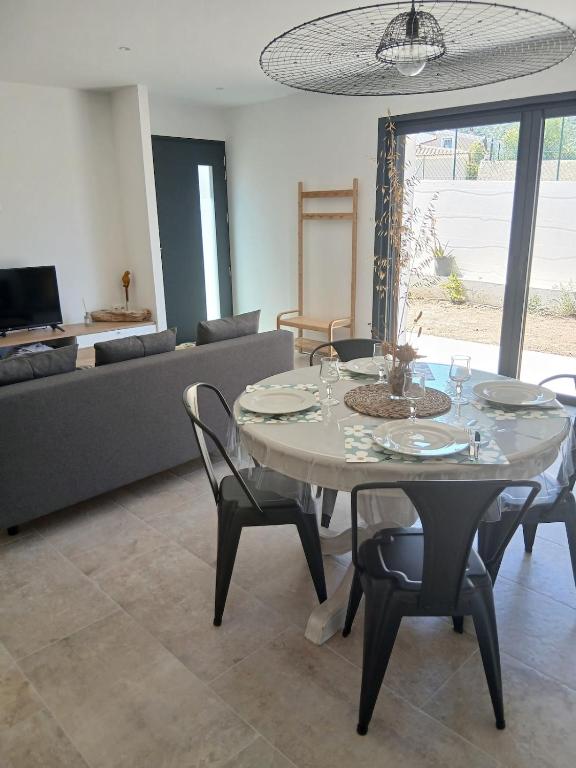 a living room with a table with chairs and a couch at charmante maison neuve proche plage et commerces in Calvi