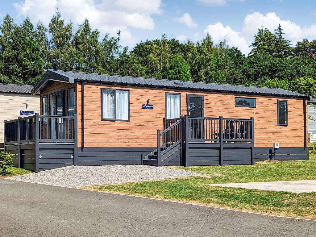 a large wooden cabin with a porch at Stonewood Country Lodge in Kelsall