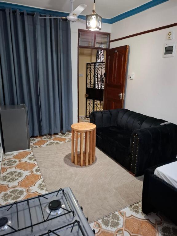 a living room with a black couch and a table at Studio Apartment Naivas Mwembe tayari Cbd in Mombasa