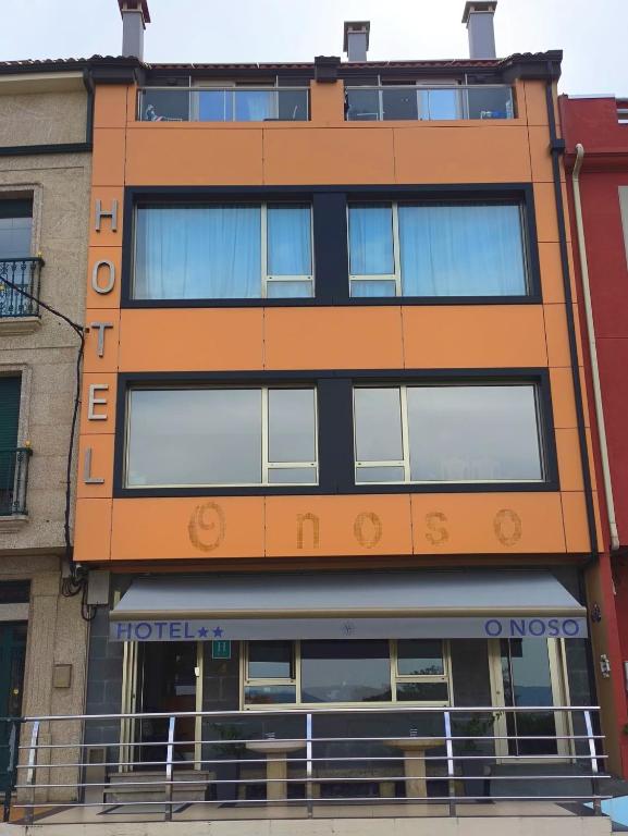 an orange building with a lot of windows at Hotel O Noso Portosin in Portosin