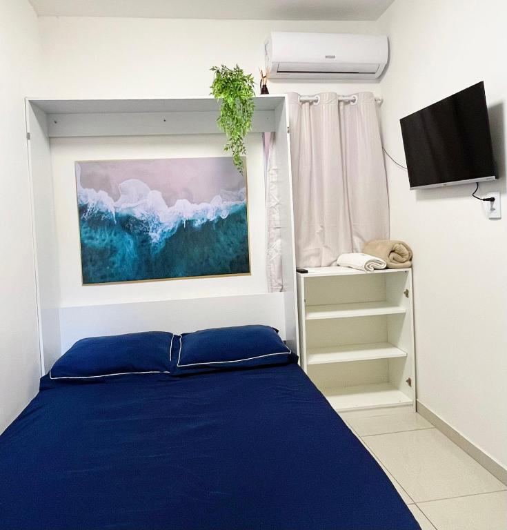 a bedroom with a blue bed and a tv at Studio privativo com Ar condicionado in Lauro de Freitas