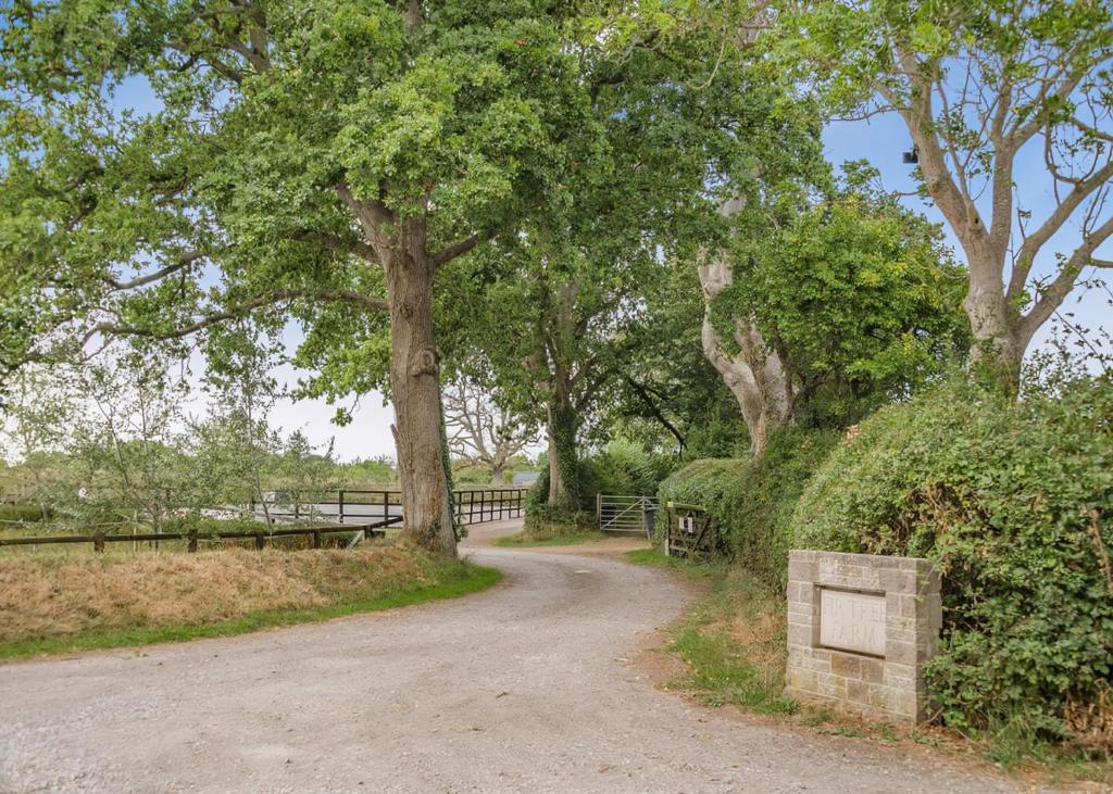 a dirt road with trees and a fence at Firtree Farm Lodges in Yeovil