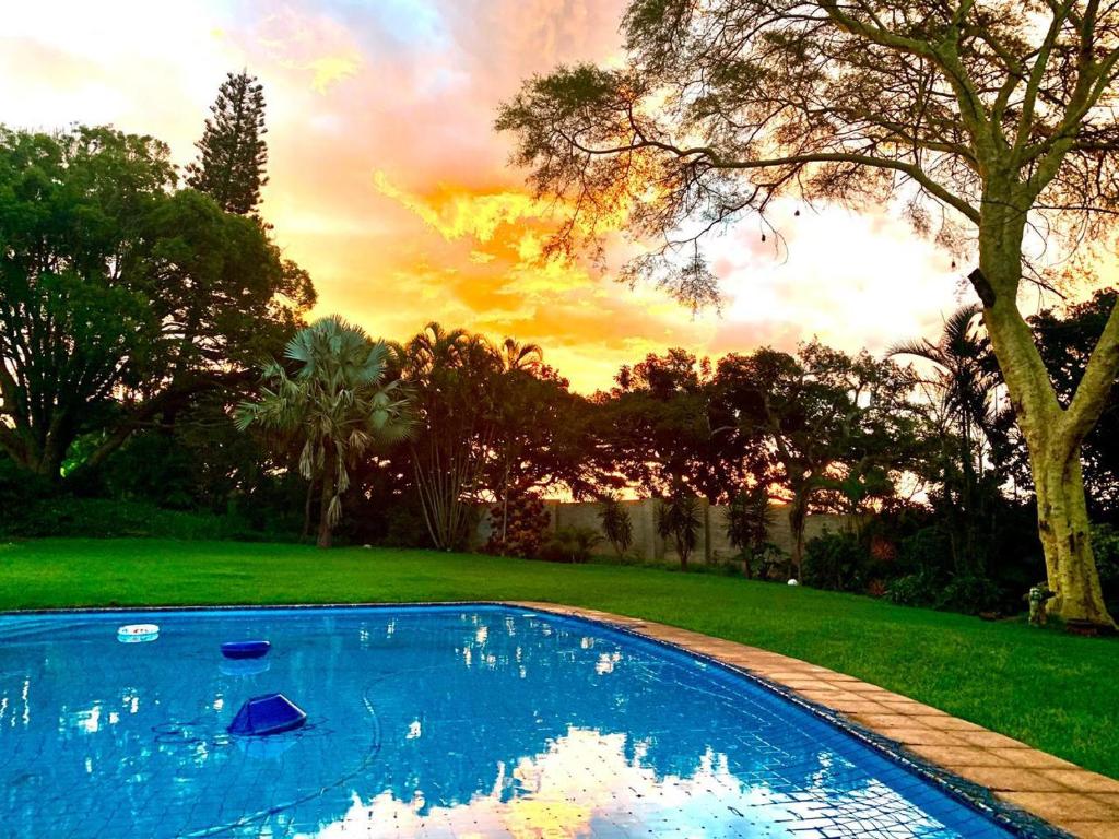 a swimming pool in a yard with a sunset at Harris Estate Country Home in Ballito