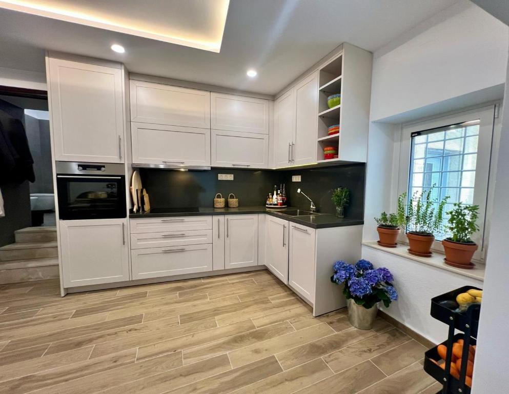 a kitchen with white cabinets and wooden floors at Saint George Cottage in Avyenikí