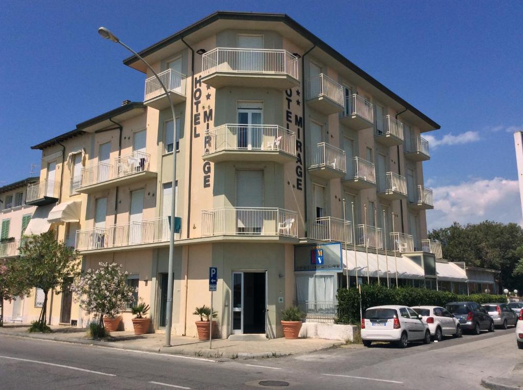 un edificio alto con coches estacionados frente a él en Hotel Mirage en Marina di Pietrasanta