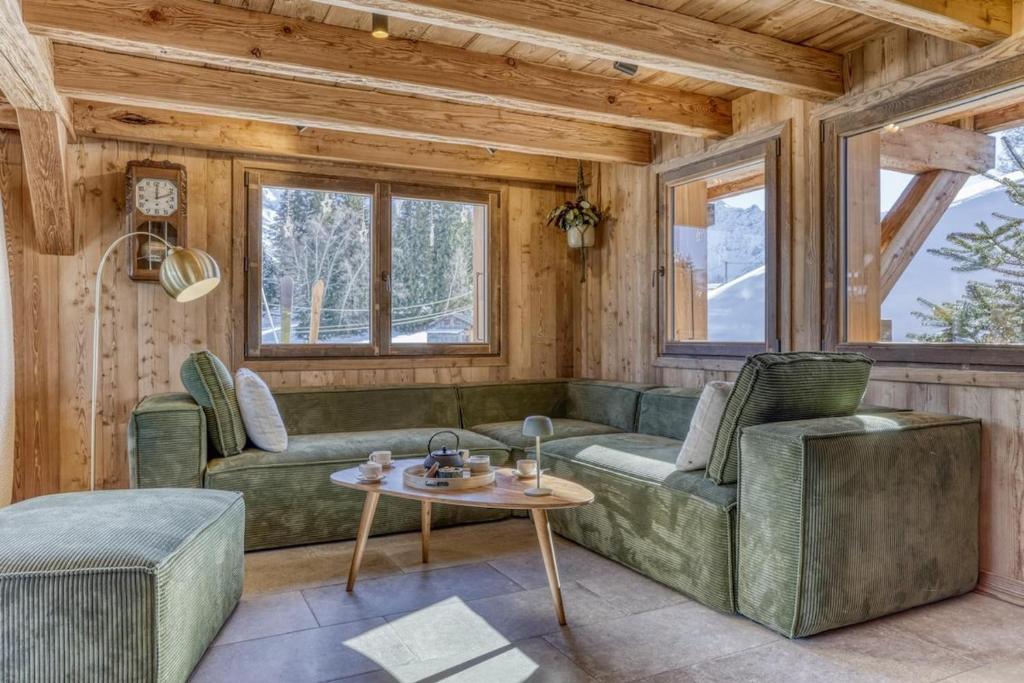 un soggiorno con un divano verde e un tavolo di Chalet le Plane a Saint-Gervais-les-Bains