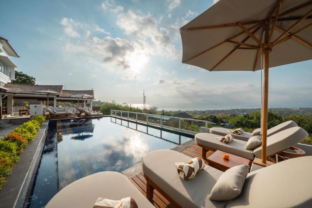 een zwembad met ligstoelen en een parasol bij Nyuh Gading HILL in Nusa Lembongan