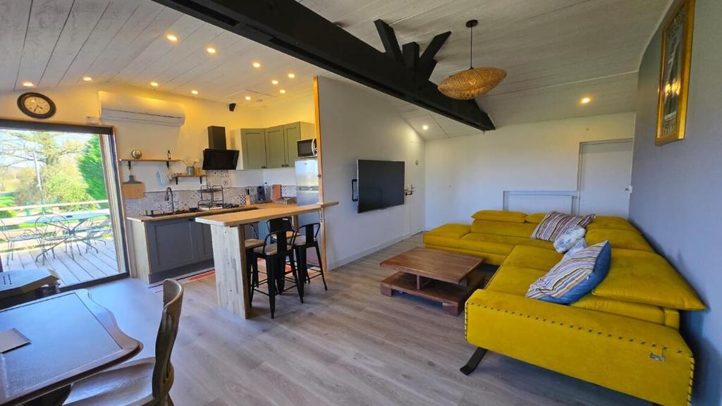 a living room with a yellow couch and a kitchen at Appartement de Charme in Baugé-en-Anjou