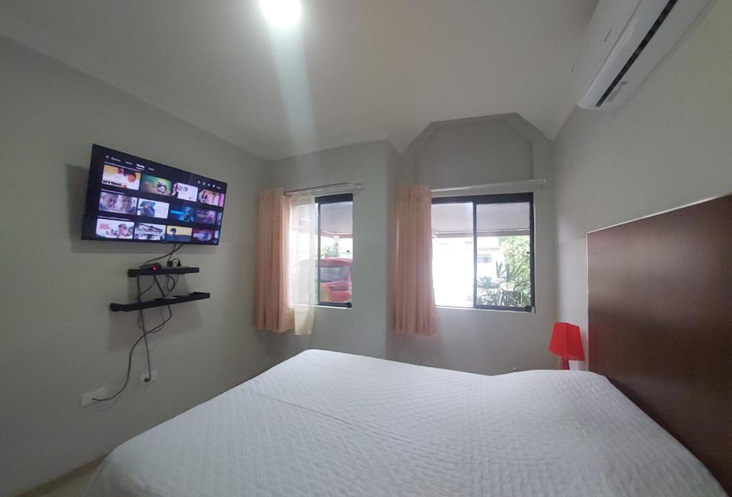 a bedroom with a white bed and two windows at PEQUEÑO y ACOGEDOR DEPARTAMENTO CON GARAJE y recibe PEQUEÑOS PELUDITOS in Santa Cruz de la Sierra
