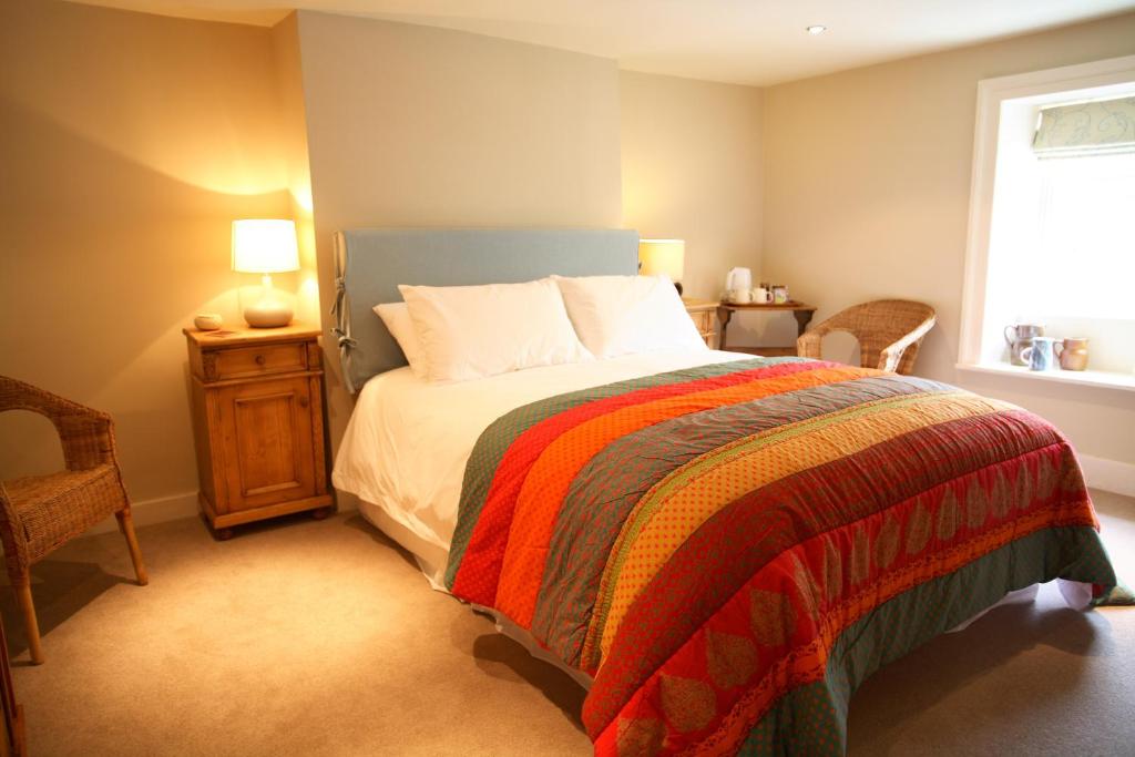 a bedroom with a bed with a colorful blanket and a window at The Scott Arms in Kingston