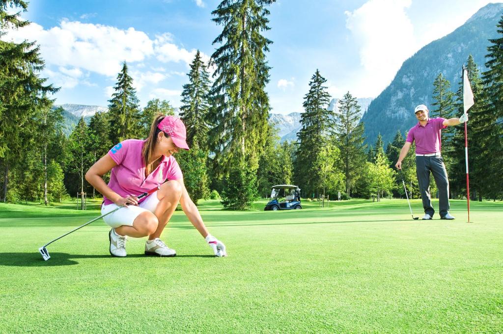 a man and a woman playing golf on a golf course at Verwöhnhotel Kristall in Pertisau