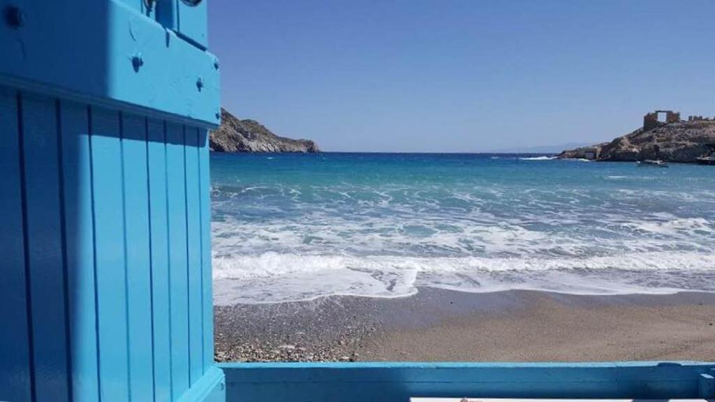 - un bâtiment bleu sur une plage à côté de l'océan dans l'établissement Studio Paradiso, à Plaka Milou