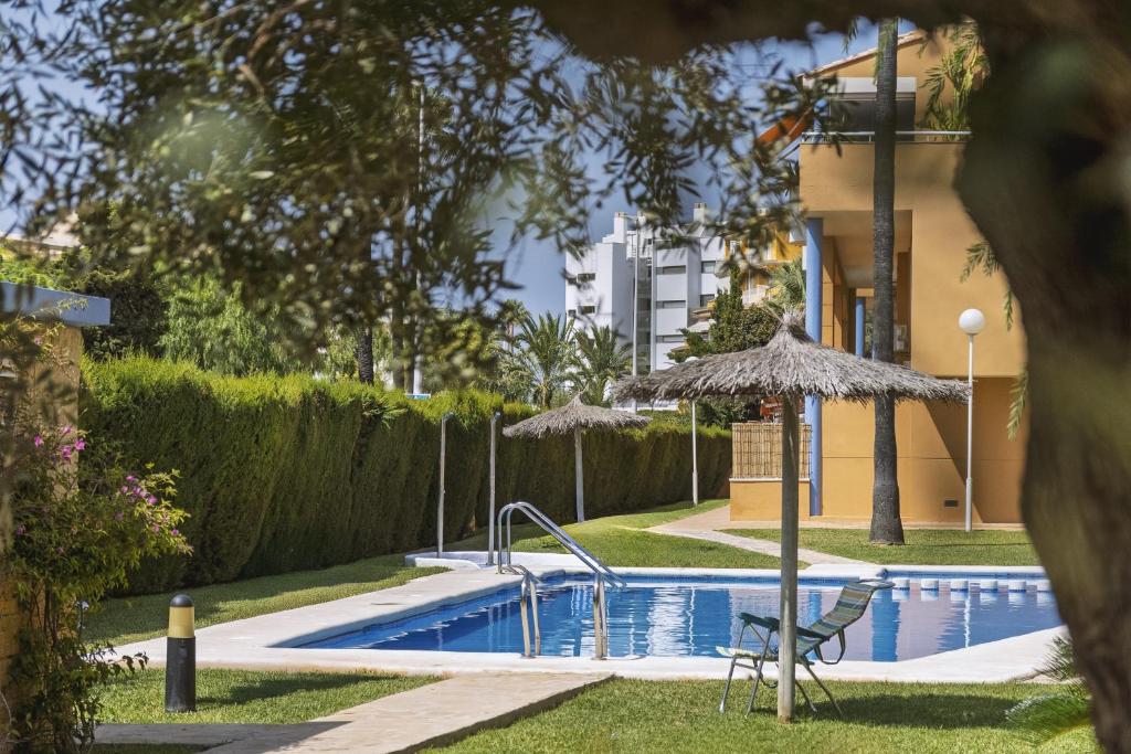 a swimming pool with a chair and an umbrella at El Velero in El Tosalet