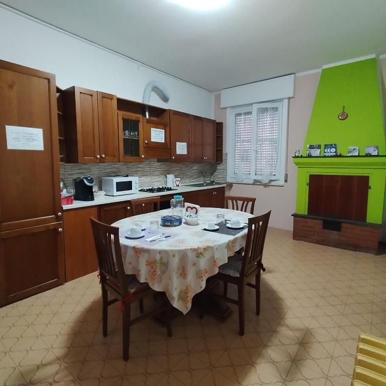 a kitchen with a table with chairs and a kitchen with green walls at La Casetta Di Cotignola in Cotignola