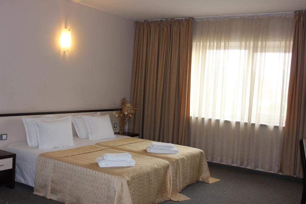 a hotel room with a bed with towels on it at Kendros Hotel in Plovdiv