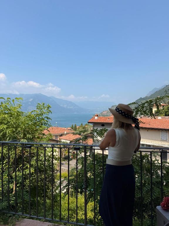 a woman standing on a balcony looking at the ocean at Matteo Lago in Sale Marasino