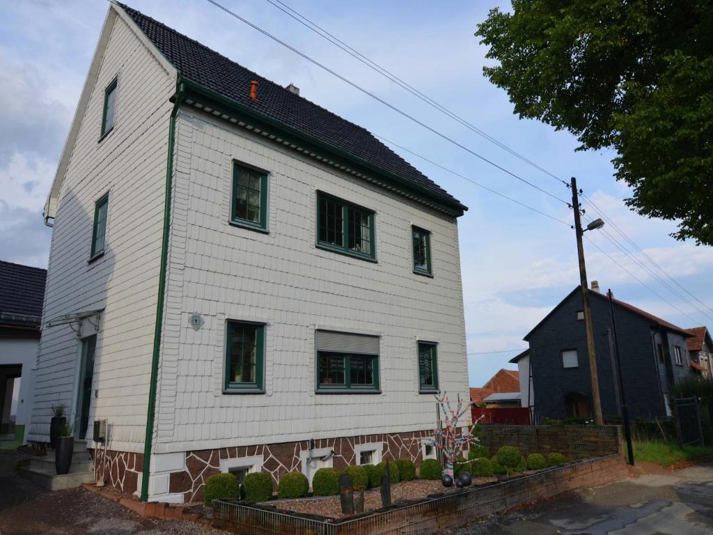 a white house with a black roof and windows at Charming Forest Escape for Two in Langewiesen