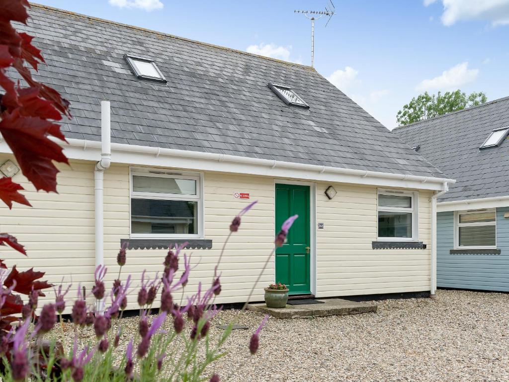 a white house with a green door and flowers at Jubileum Lodge Uk27999 in Watton