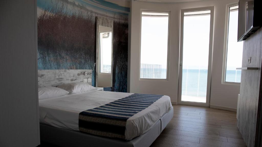 ein Schlafzimmer mit einem Bett in einem Zimmer mit Fenstern in der Unterkunft Hotel Negretto in Caorle
