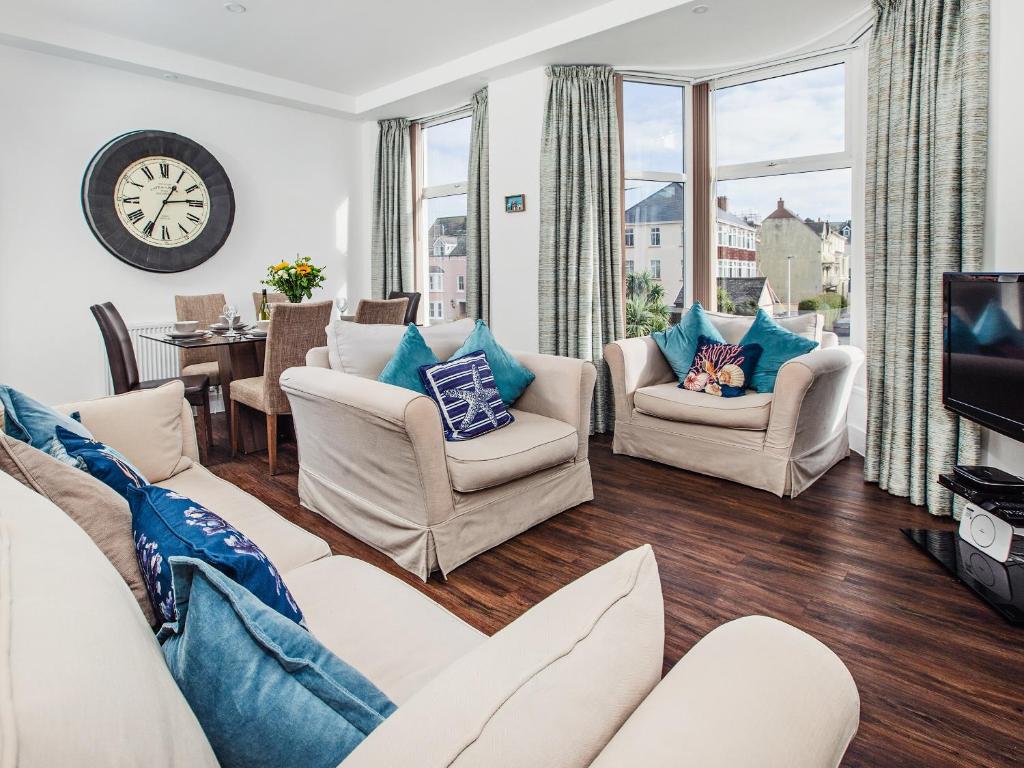 a living room with white furniture and a tv at Dyma Y Bywyd in Tenby