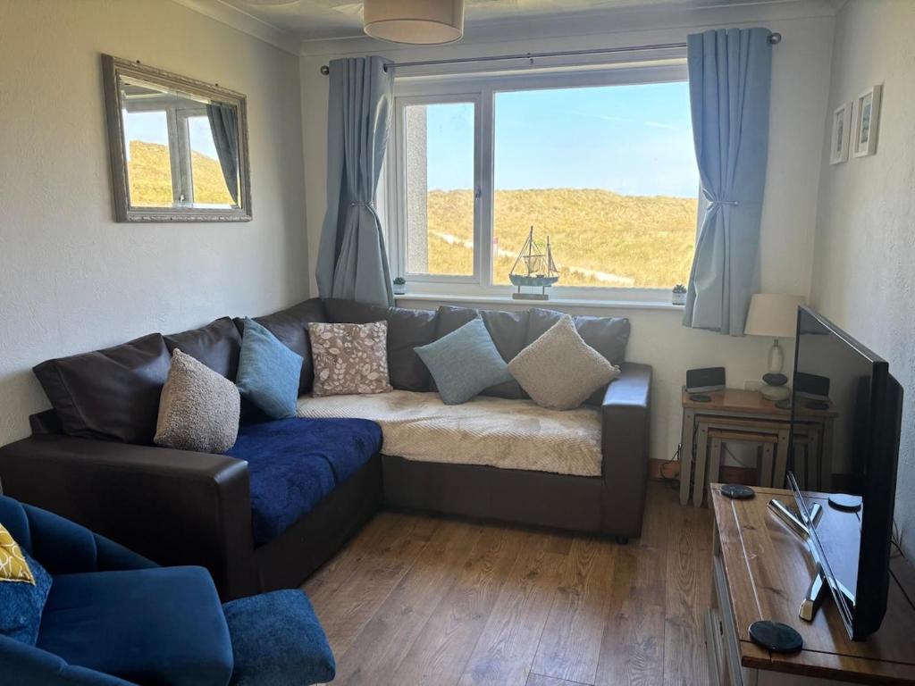 a living room with a couch and a large window at Dunes View - Atlantic Bay in Perranporth