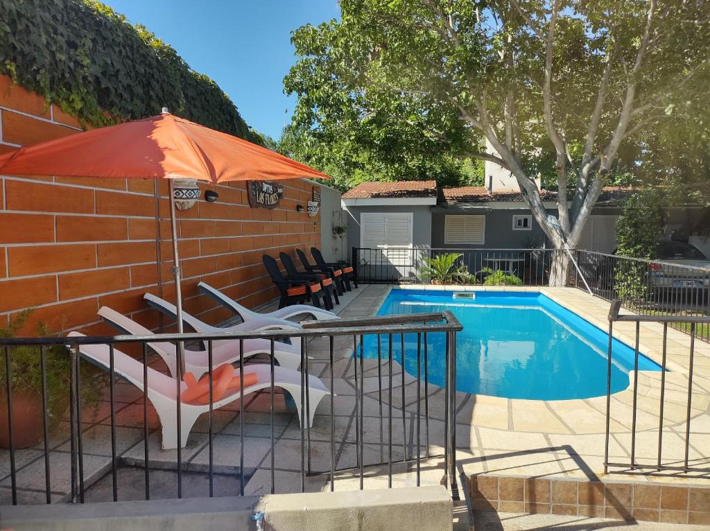 una piscina con sombrilla naranja junto a una casa en Apartamentos Las Flores, en Villa Carlos Paz