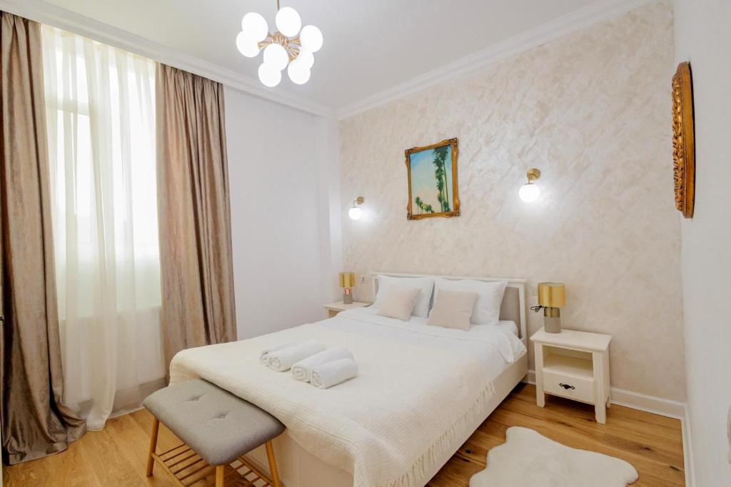 a white bedroom with a white bed and a chair at Ariniș Best Bucovina Apartament in Gura Humorului
