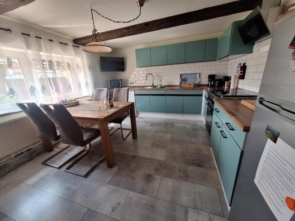 eine Küche mit einem Holztisch und Stühlen darin in der Unterkunft FeWo Am alten Holzplatz in Drübeck