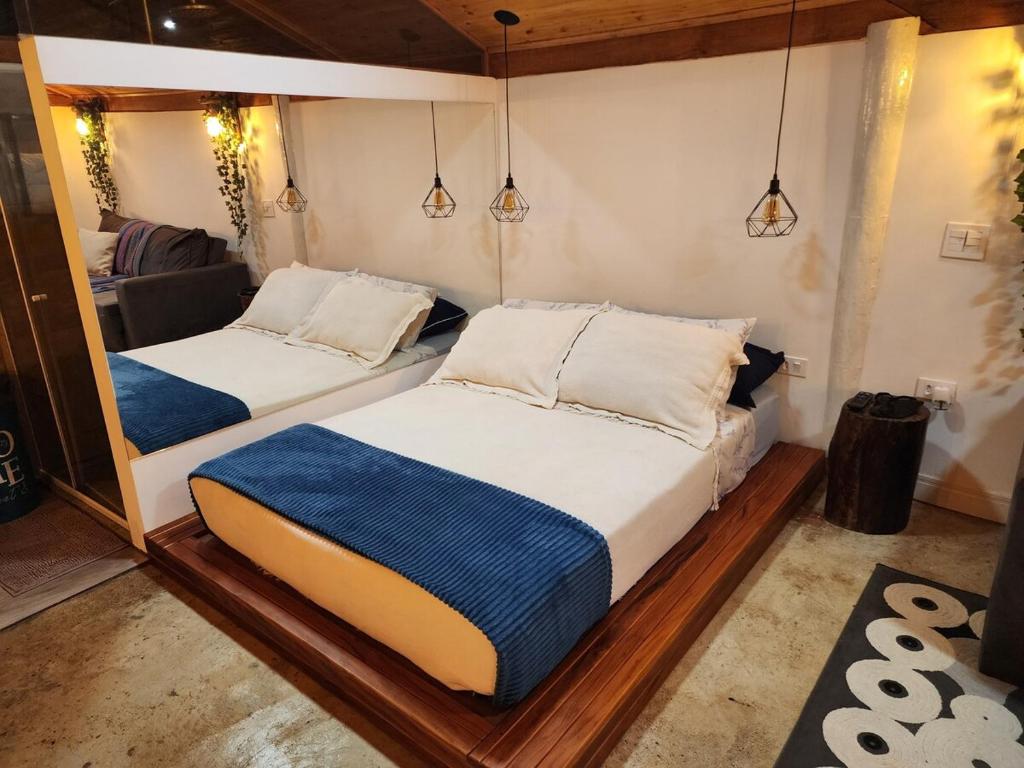 two beds in a room with a mirror at Na Serra Chalés in Itapecerica da Serra