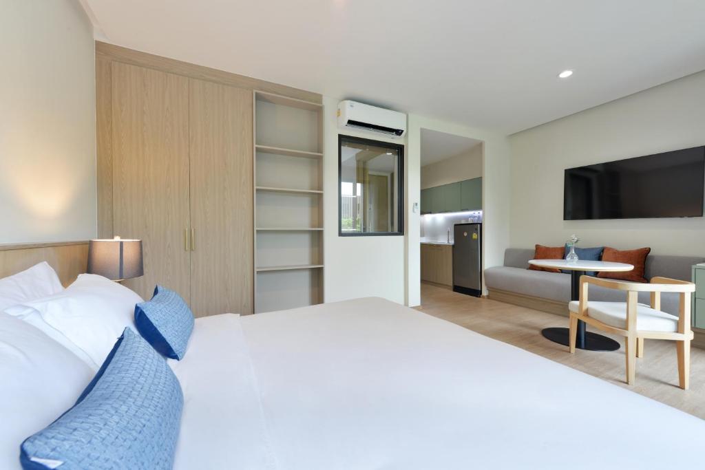 A bedroom view showing the sitting area, television and kitchenette beyond.