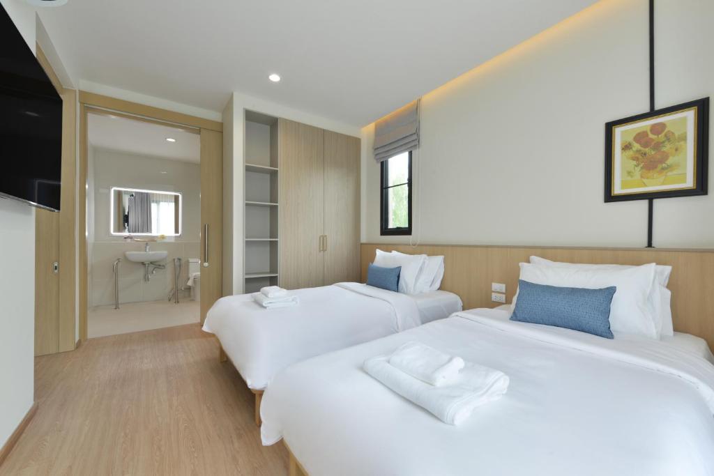 A twin bedroom with two beds, a television and a visible bathroom entrance.