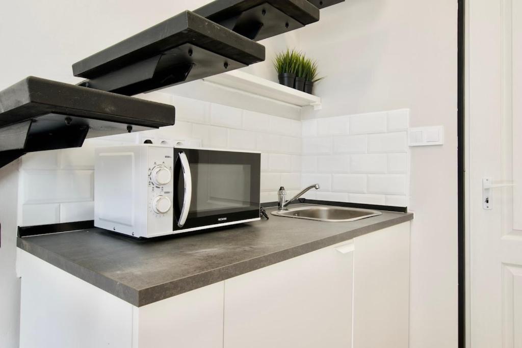 a white kitchen with a microwave and a sink at Standard Apartment by Hi5- Fehérhajó Studio in Budapest