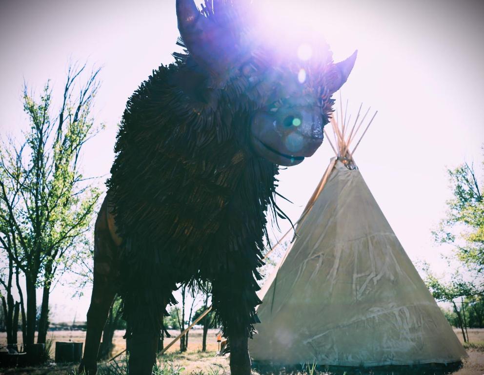 een standbeeld van een geit die naast een tipi staat bij Kiowa Teepee at Nomad Landing in Clayton