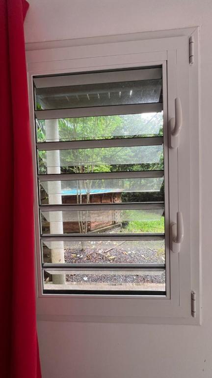 a window with a blinds on a door at Chambre villa la mahaudiere in Îlet à Christophe